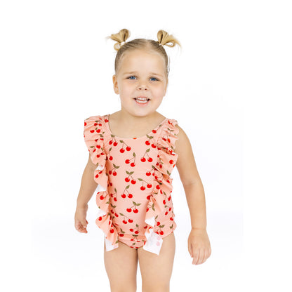 Young girl wearing a pink swimsuit with cherry pattern on a white background