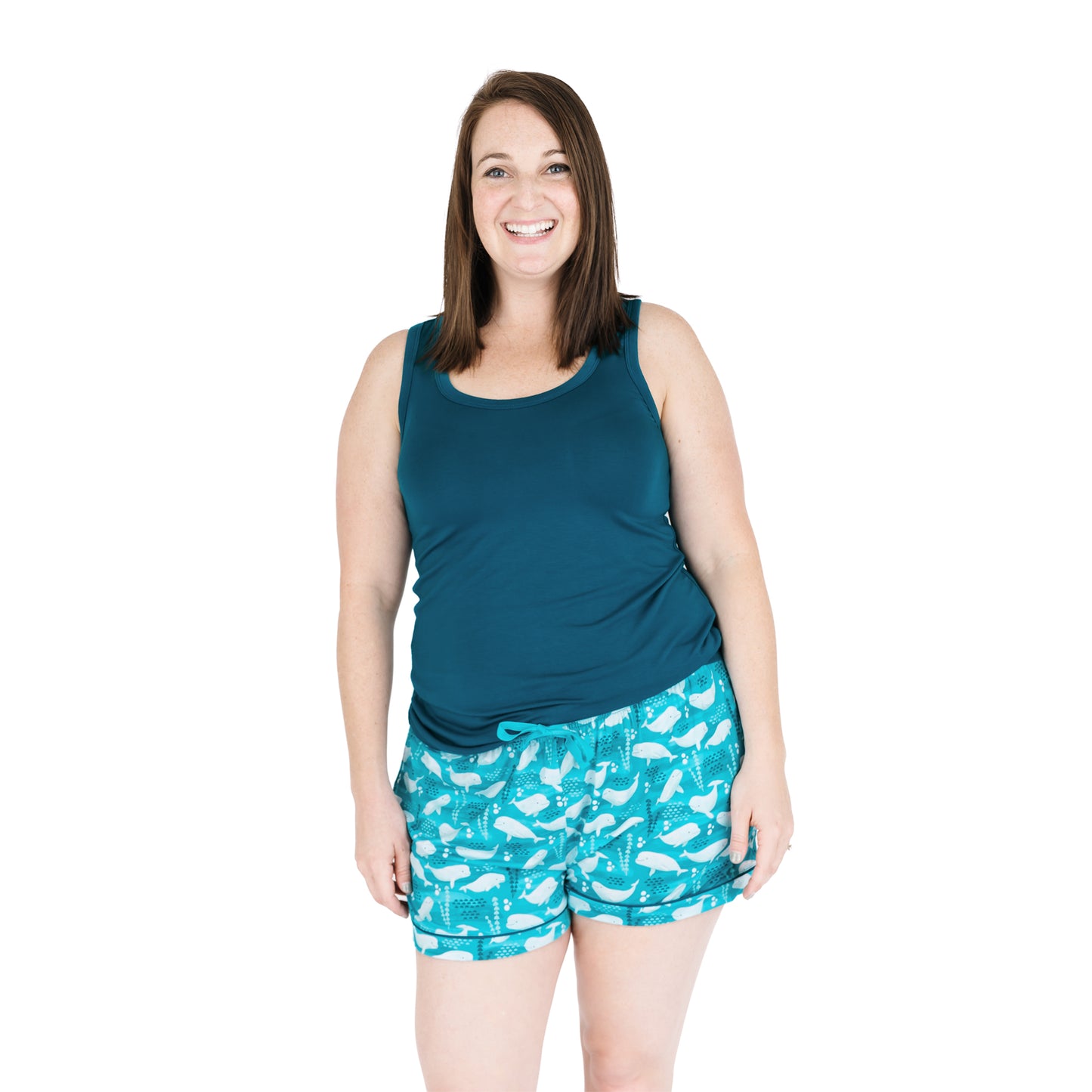 Woman wearing a teal tank top and patterned shorts on a white background