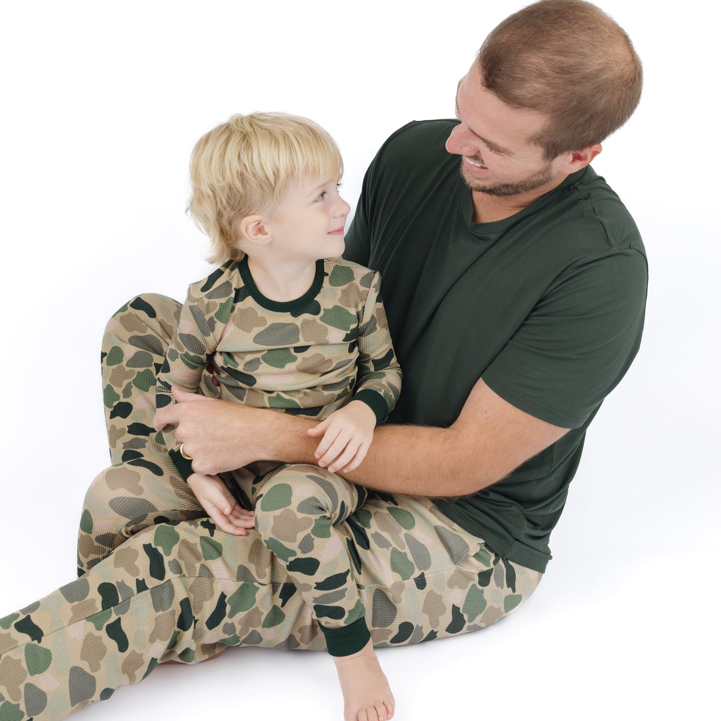 little boy in camo print two piece pajama and dad wearing matching camo pants