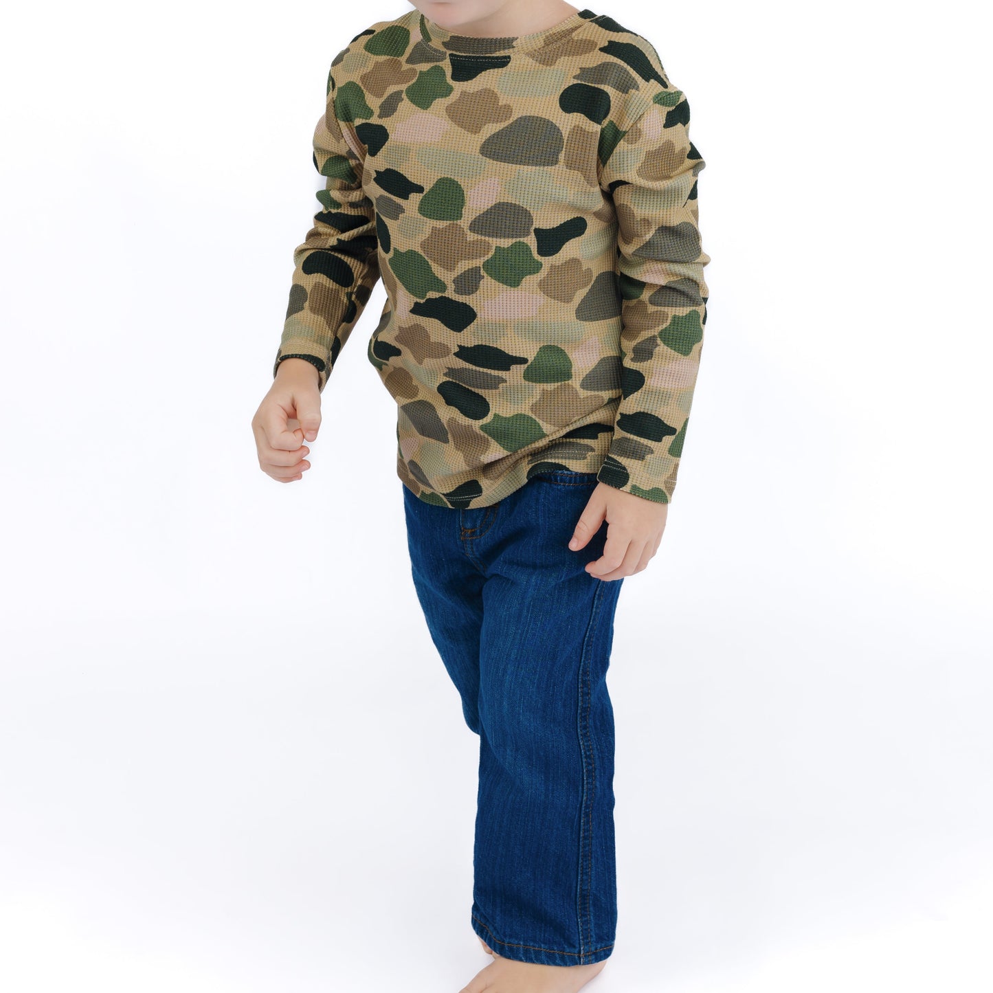 little boy wearing camo print long sleeve and jeans.