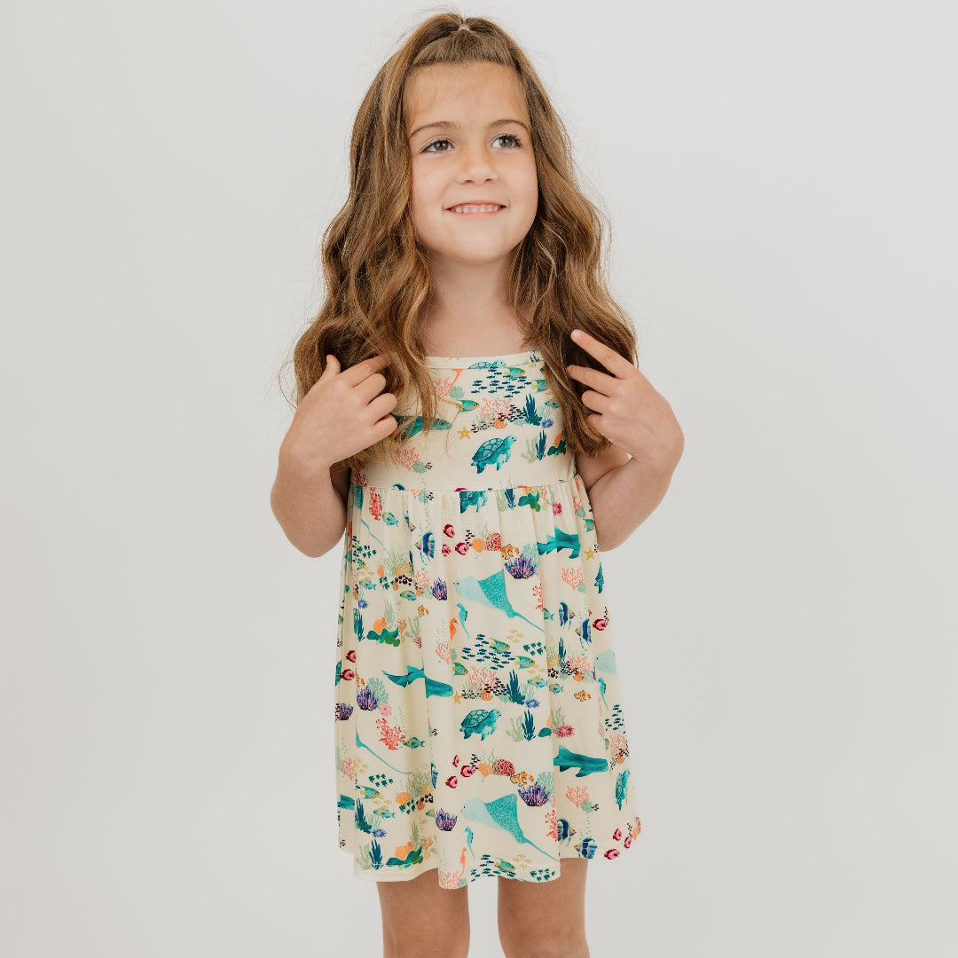 Toddler girl wearing out Emerson and Friends Coral Reef Bamboo Sundress featuring an ocean-inspired print with sharks, sea turtles, and coral, made from ultra-soft and breathable bamboo fabric for a lightweight and comfortable summer outfit.