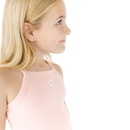 Young girl wearing a pink tank top with a daisy brooch on a white background