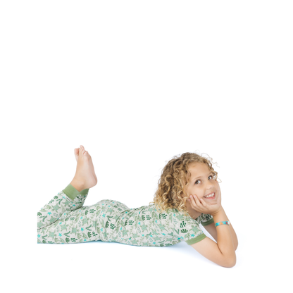 Child wearing a green sea turtle pajama set lying on a white background