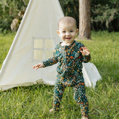 baby wearing dark green zippie with floral print.