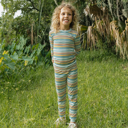 boy wearing striped print pajama set on greenery background. 