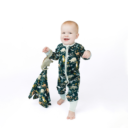 Baby wearing a dinosaur-patterned onesie on a white background
