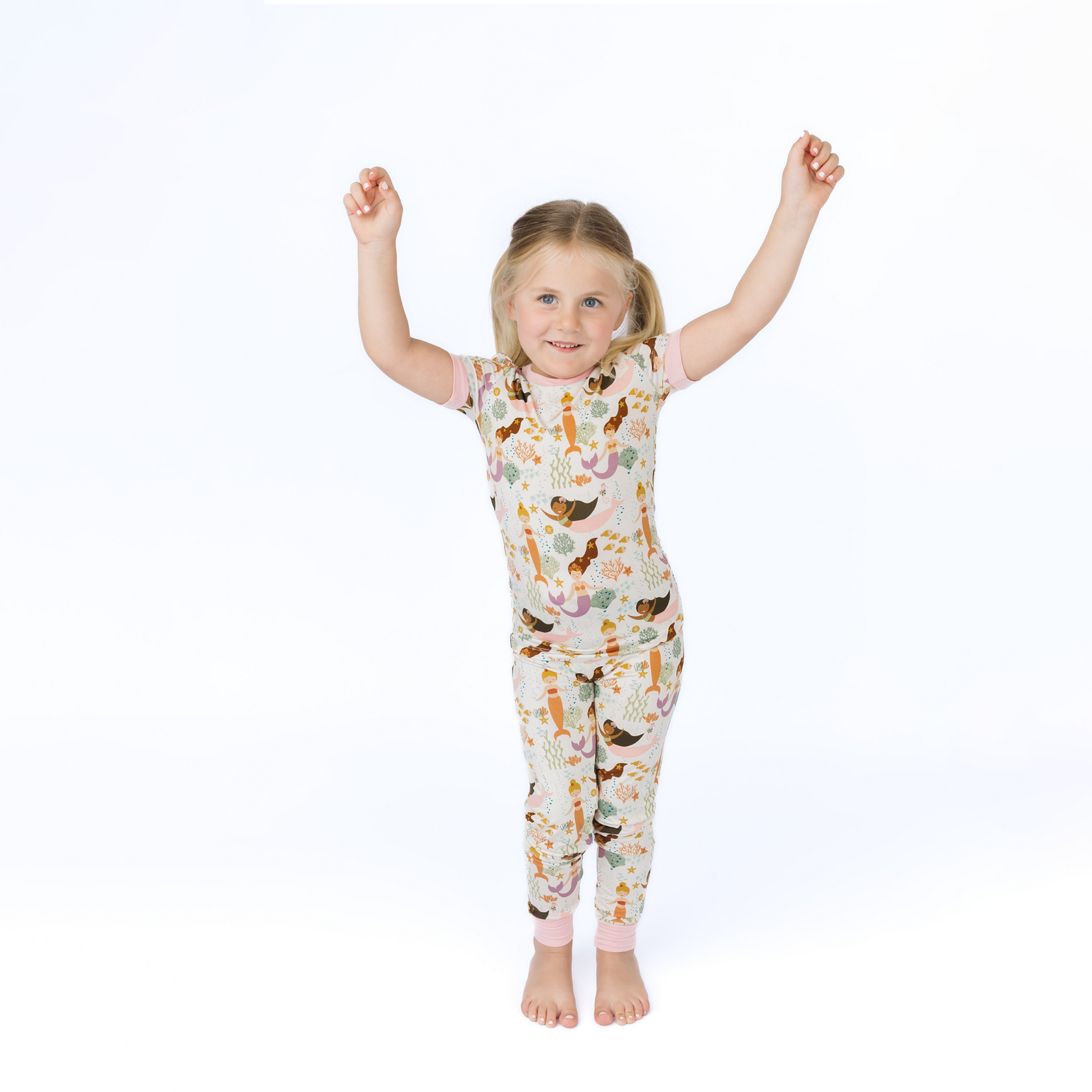 Child wearing a mermaid patterned pajama set on a white background