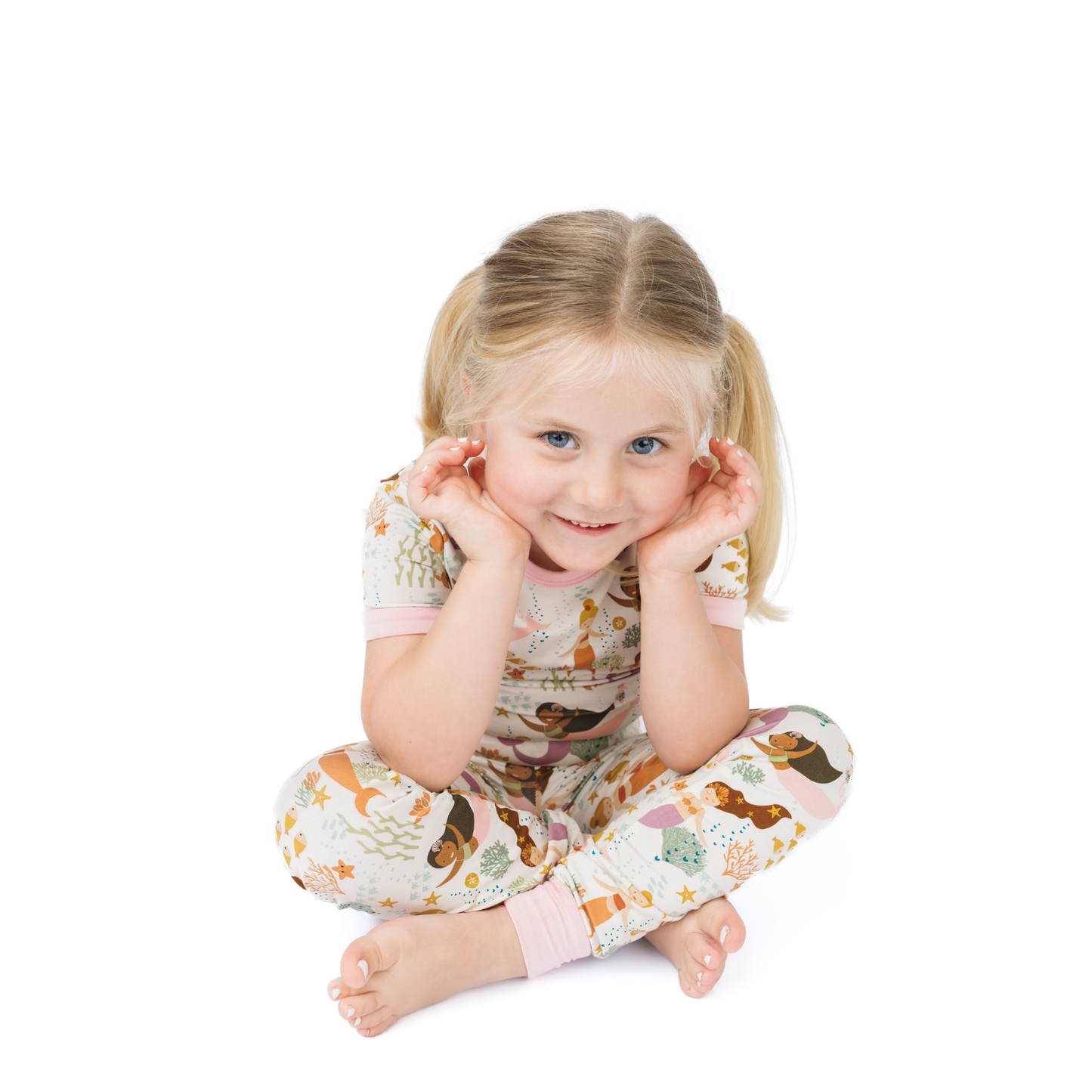 Child wearing a patterned outfit with cartoon mermaids on a white background