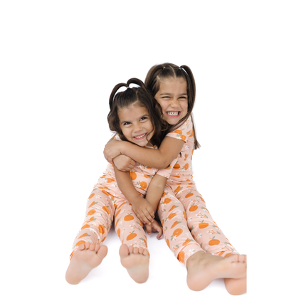 Two children wearing matching pajamas with a white background