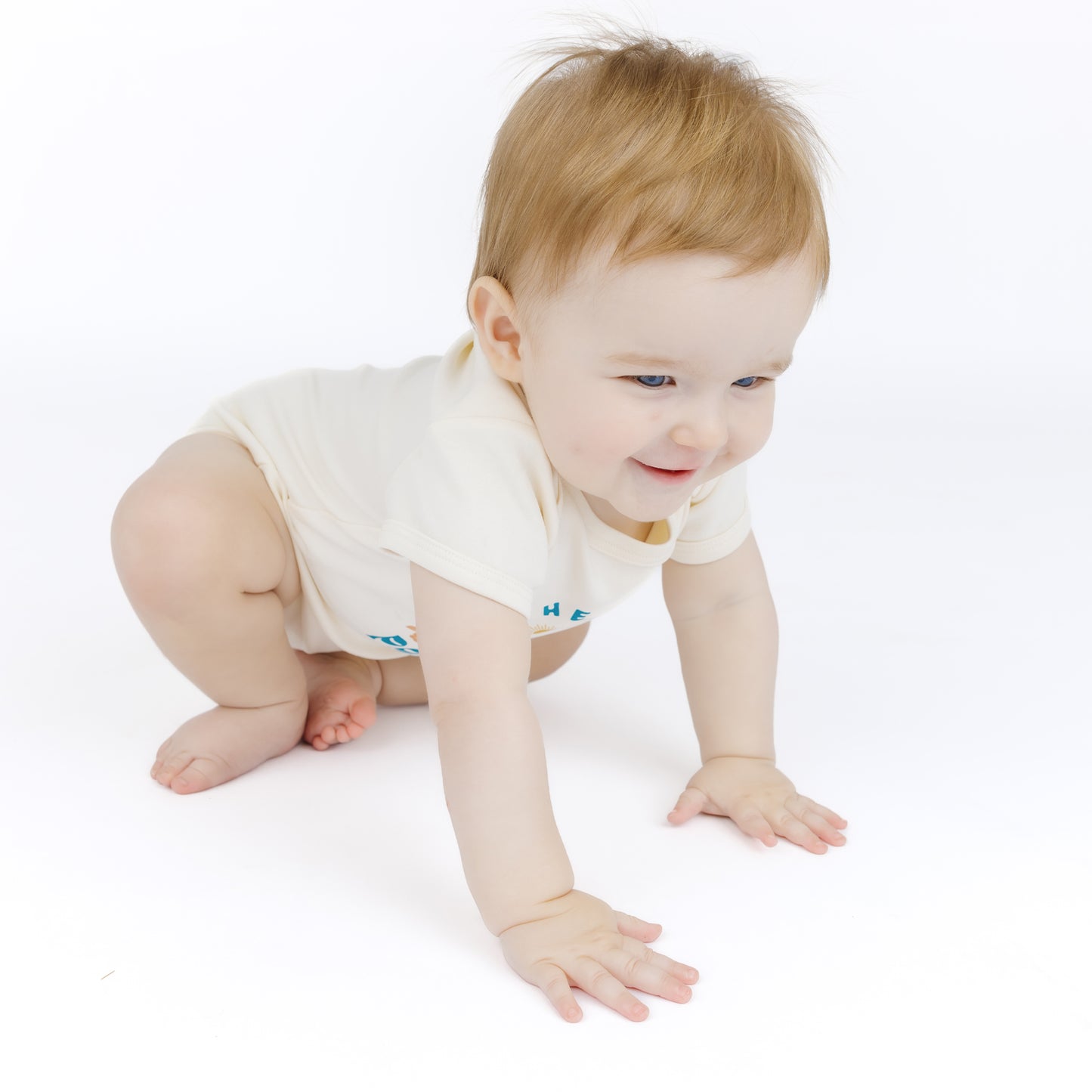 Baby in a white bodysuit crawling on a white surface