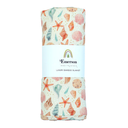 Our luxury bamboo blanket in a sandy seashell print, rolled with a label. Twin Size.