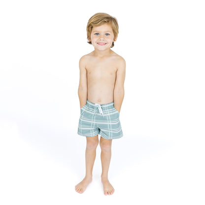 Young boy wearing striped swim shorts on a white background