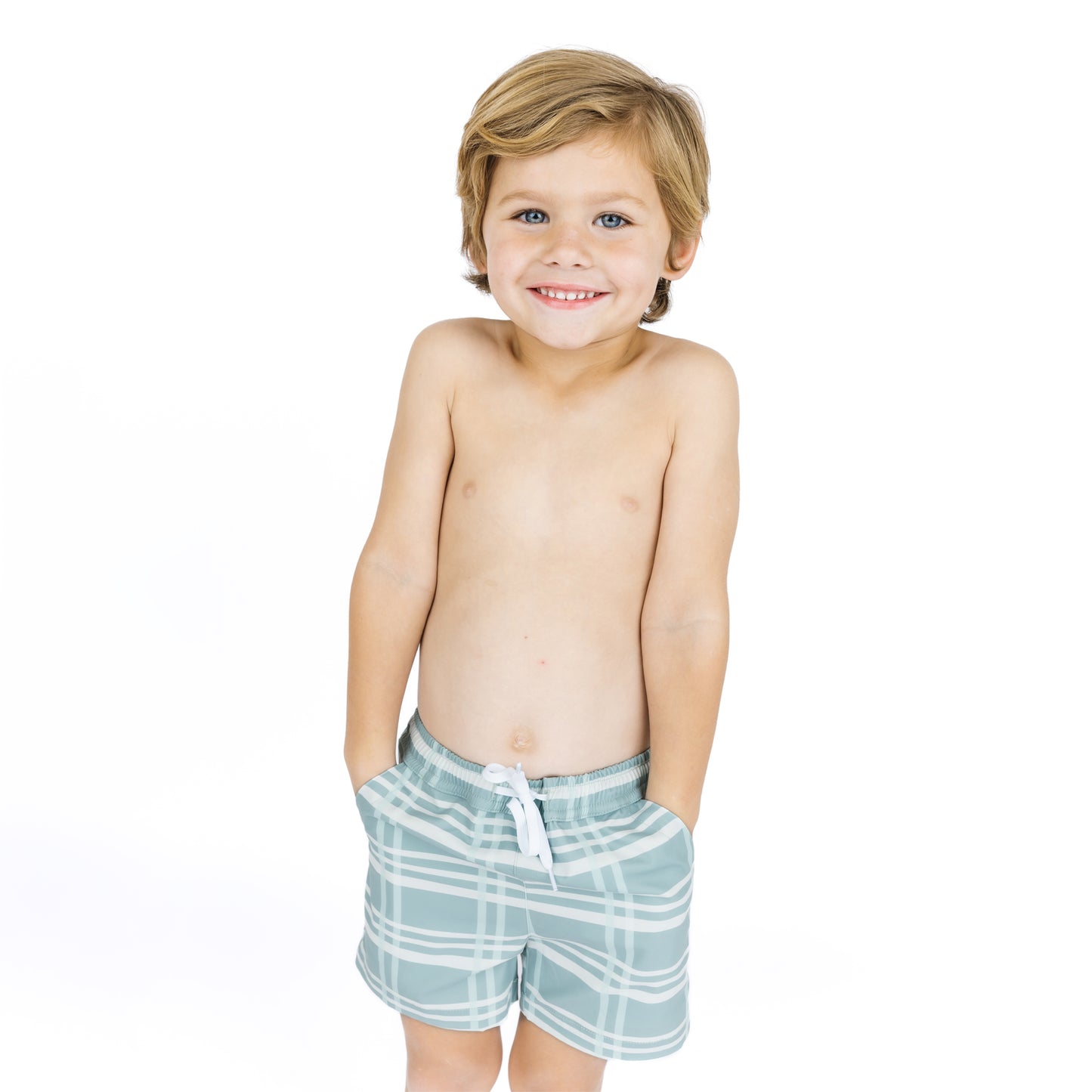 Young boy wearing light blue plaid shorts on a white background