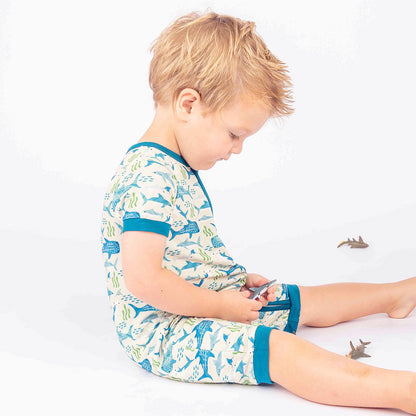 Little boy sitting while wearing our Shark Friends Shortie Romper.