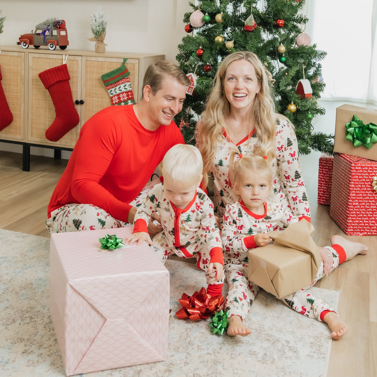 Family opens presents by the tree in matching Cozy Christmas bamboo pajamas with relaxed fit pants.