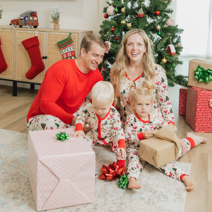 Family opens gifts by the tree wearing Cozy Christmas bamboo pajamas, showcasing festive jogger pants with red cuffs.