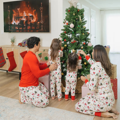 Family in matching pajamas decorating a Christmas tree in a cozy living room.