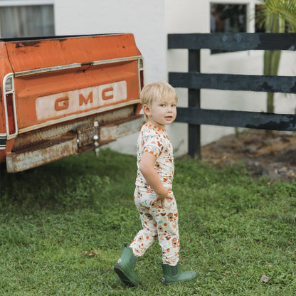 Two children wearing Cozy Cottage bamboo pajama pants set walking near a red farm truck.