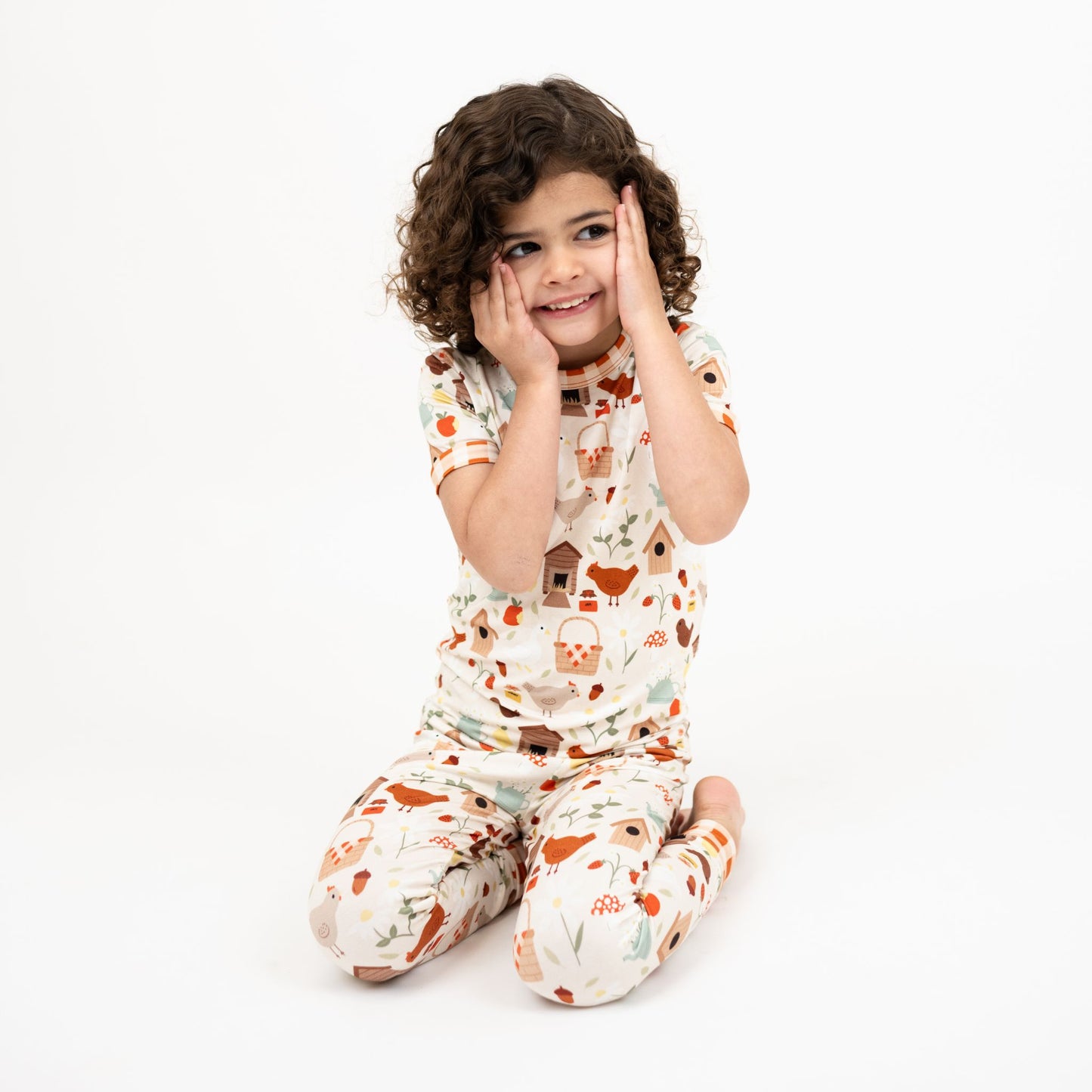 Girl wearing Cozy Cottage bamboo short sleeve pajama pants set sitting with hands on face.
