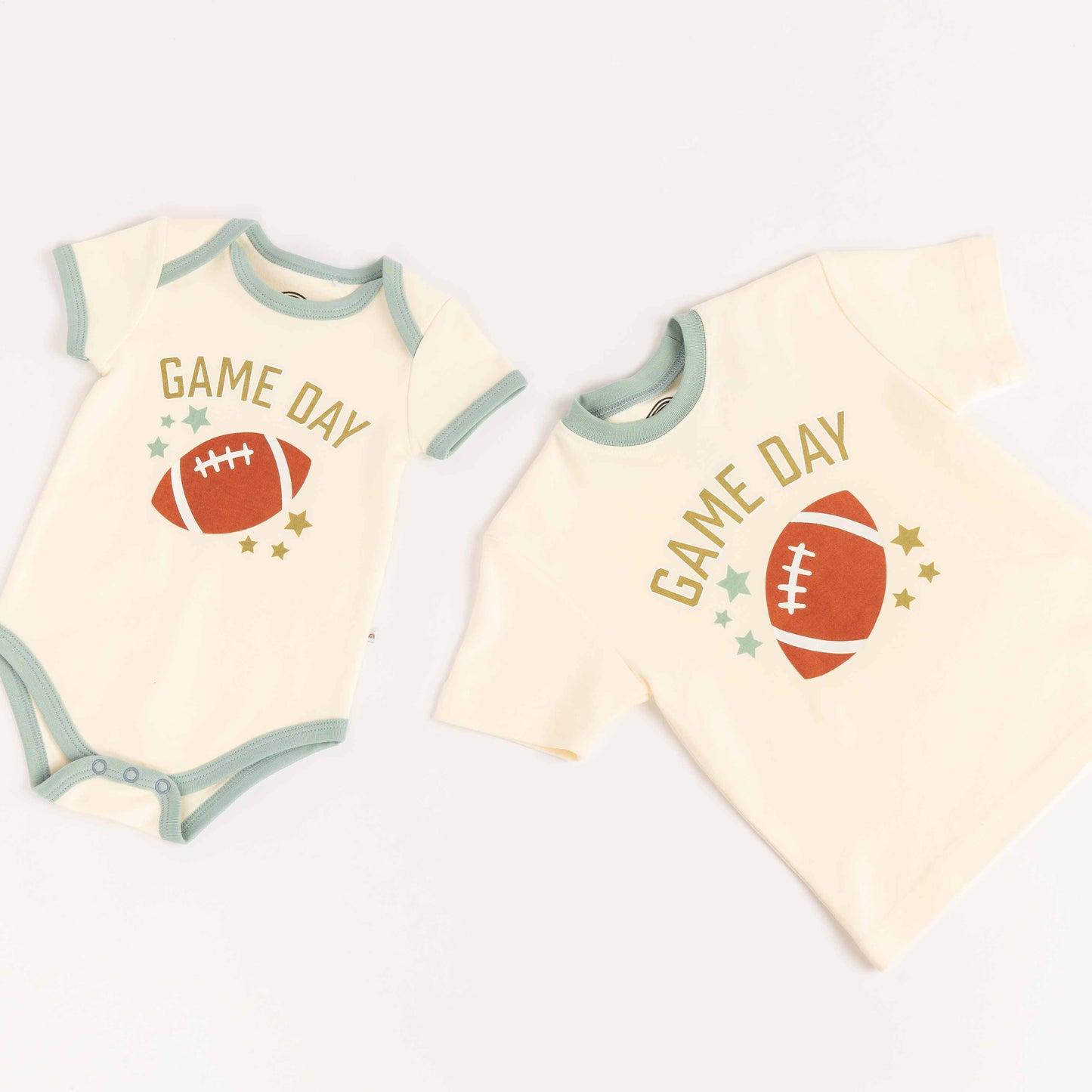Flat lay of cotton tee-shirt, and cotton bodysuit laying on white background. Both say "Game Day" with a football on them