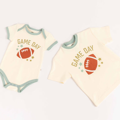Flat lay of cotton tee-shirt, and cotton bodysuit laying on white background. Both say "Game Day" with a football on them