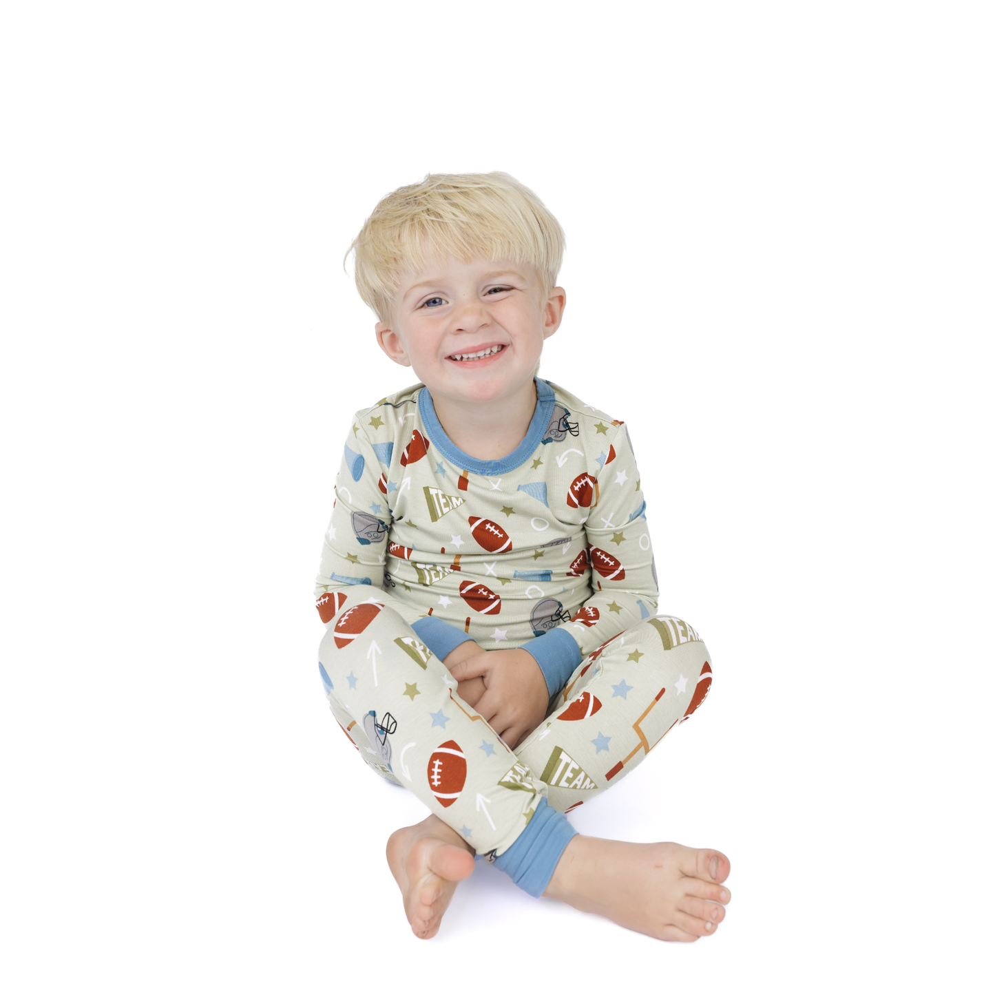 Child wearing pajamas with a pattern of footballs and stars on a white background