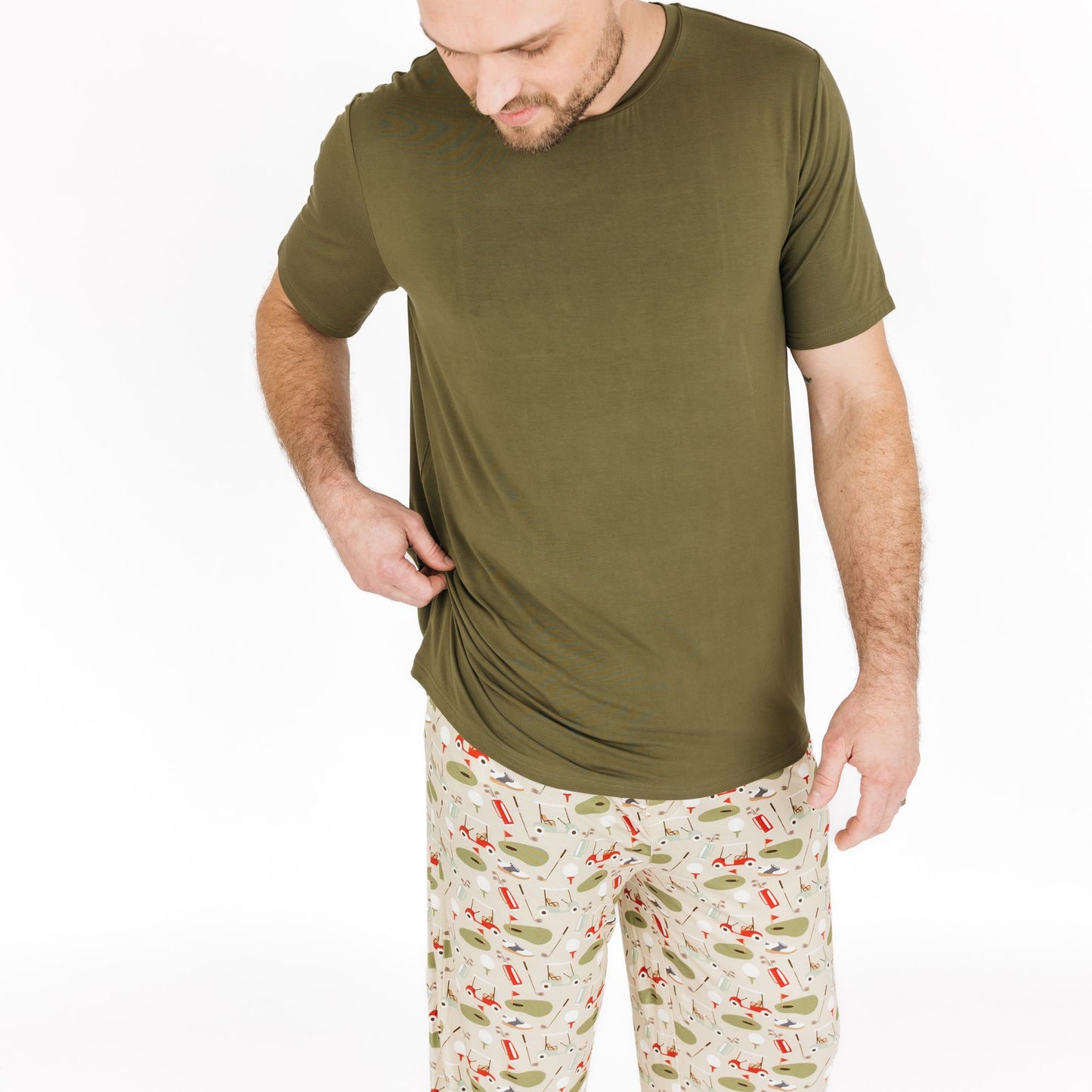 Man wearing an olive green t-shirt and patterned pants on a white background