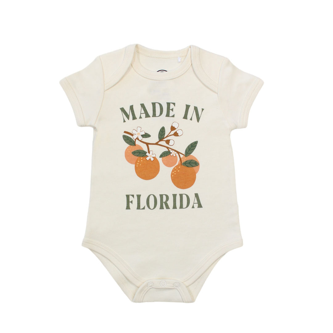 this cotton bodysuit has the phrase "made in Florida" in green print on the onesie. there is also a branch of oranges on it too. 