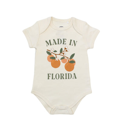 this cotton bodysuit has the phrase "made in Florida" in green print on the onesie. there is also a branch of oranges on it too. 