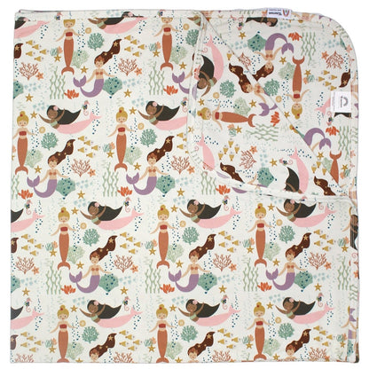 the "making waves" bamboo blanket. the "making waves" print has a diverse spread of mermaids, sea coral, starfish, fish, and bubbles all spread out in different colors. this is all put on a beige background.