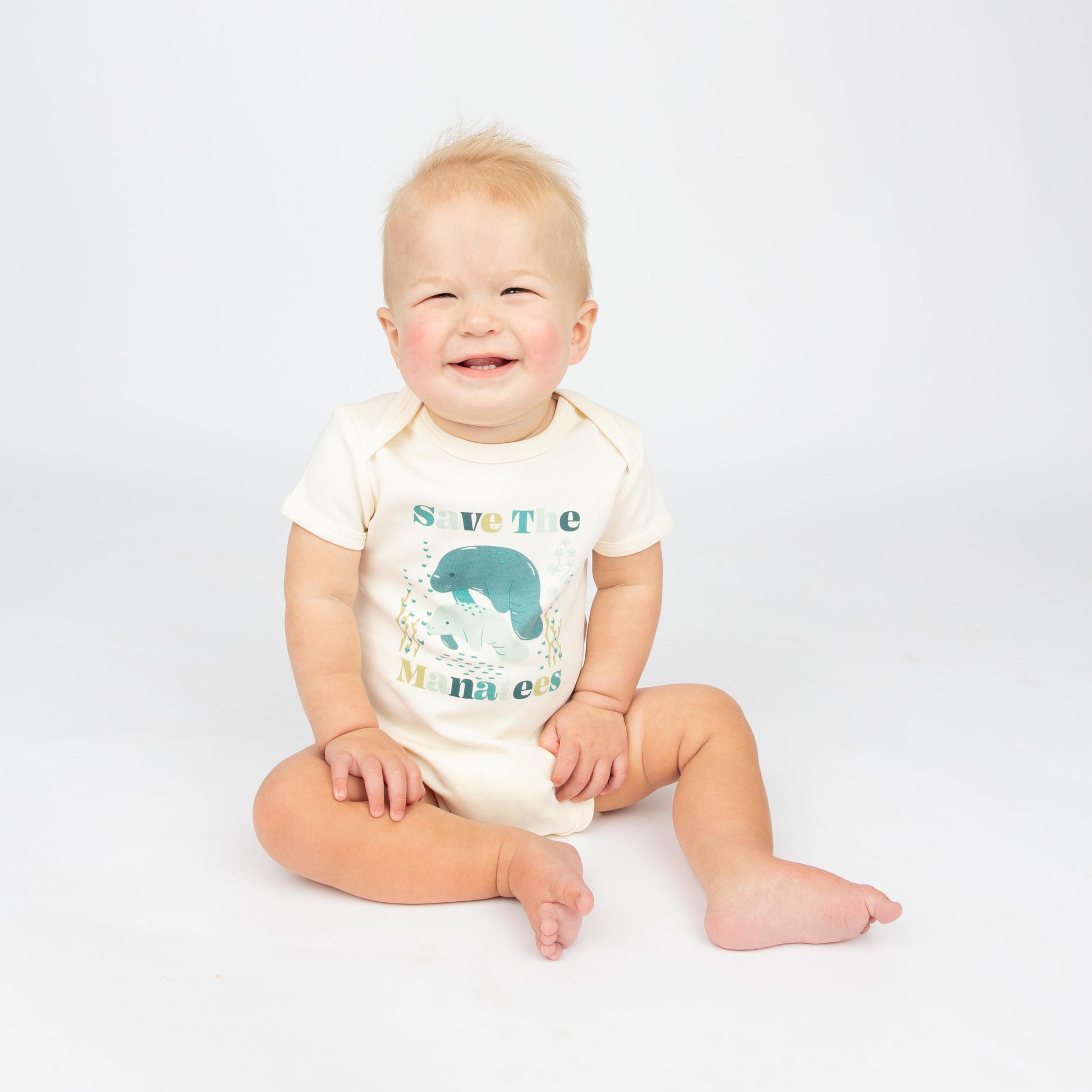 Baby wearing a Save the Manatees cotton bodysuit with a cute manatee print, featuring soft, eco-friendly fabric on a white background.