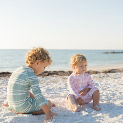 Two children playing on a sandy beach with ocean in the background