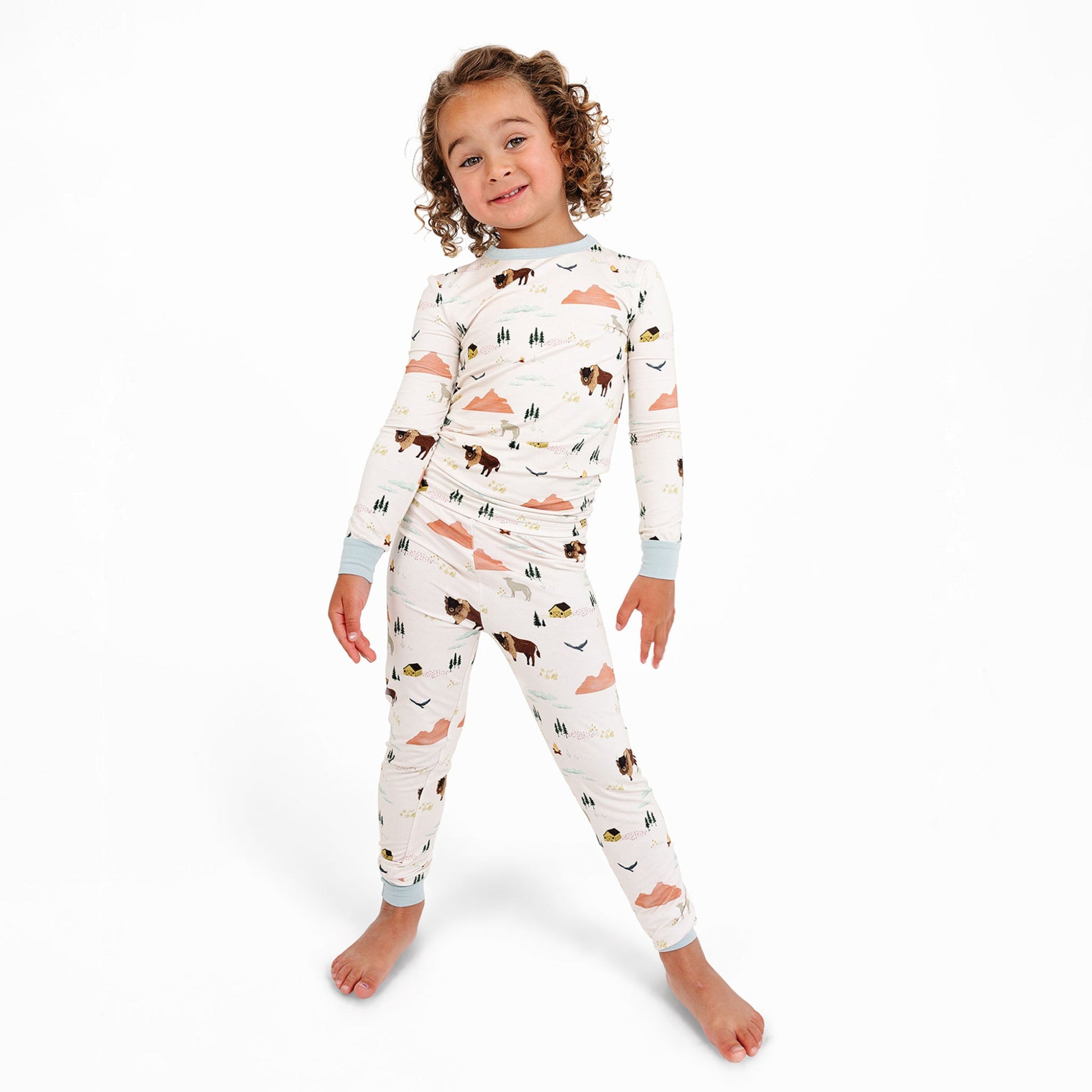 Child wearing a long-sleeve pajama set with animal pattern on a white background