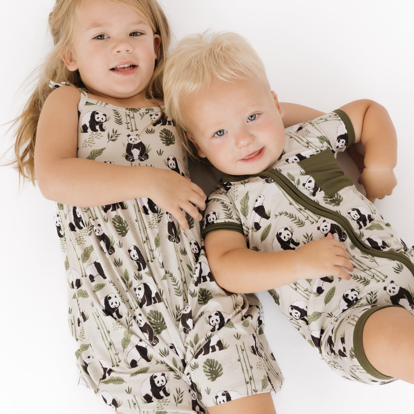 Two children wearing matching pajamas with panda patterns on a white background