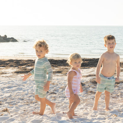 Three children on a sandy beach with ocean in the background