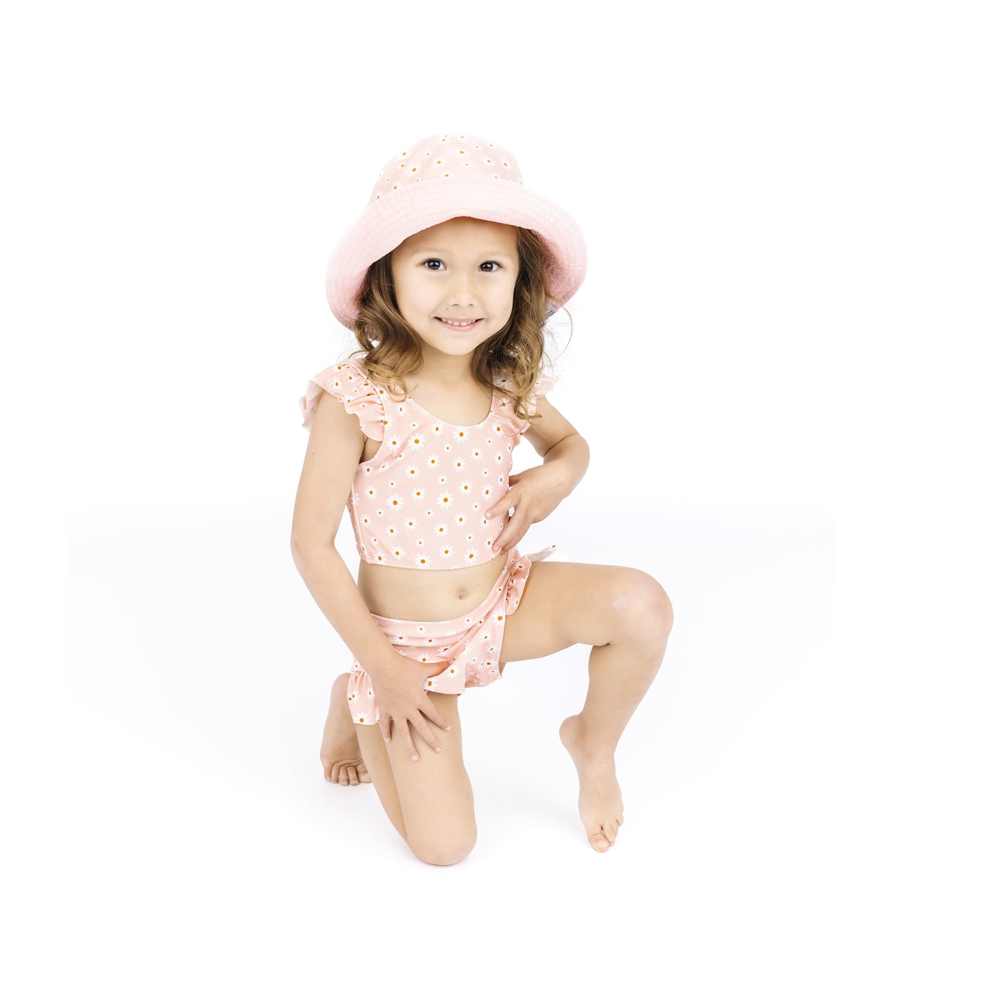 Young girl wearing a pink polka dot swimsuit and hat on a white background