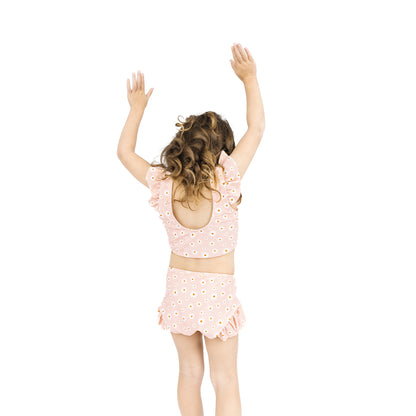 Child wearing a pink outfit with cut-out design on a white background