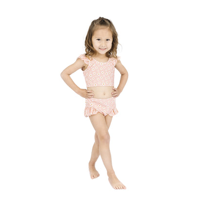 Young girl wearing a pink floral two-piece swimsuit on a white background