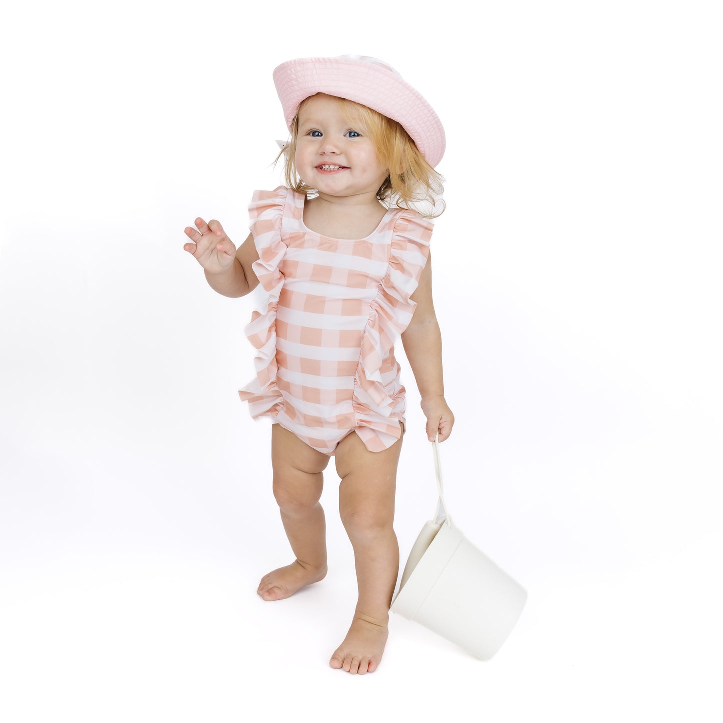 Child wearing a pink and white striped swimsuit with a matching hat on a white background