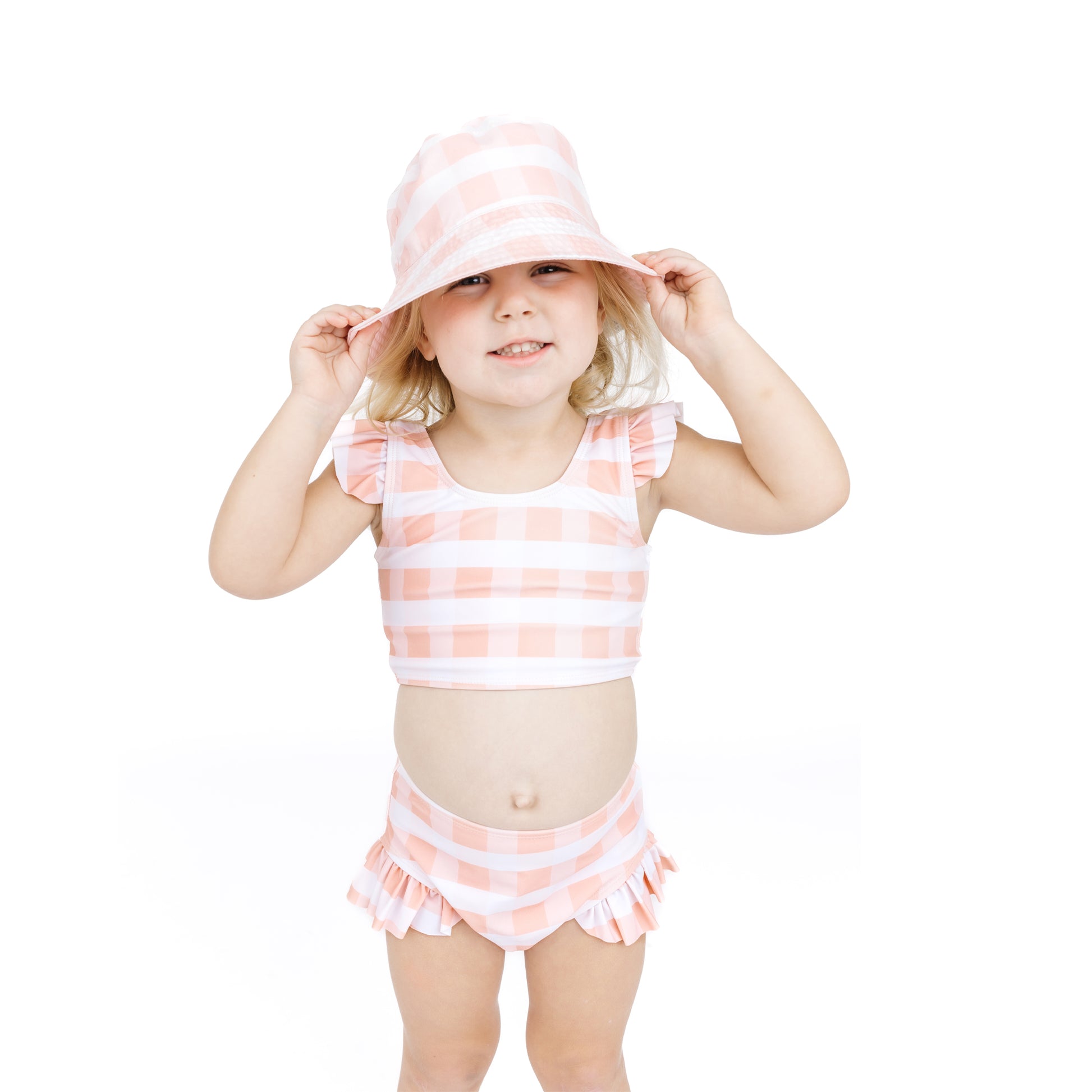 Young girl wearing a pink and white striped swimsuit and hat on a white background