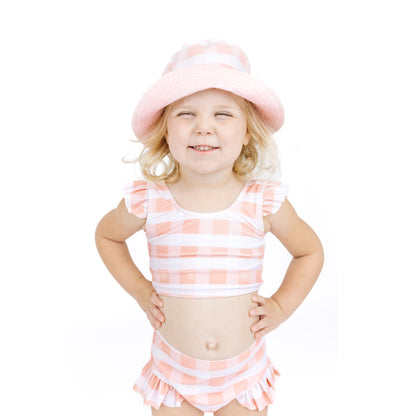 Child wearing a pink and white striped swimsuit with a matching hat on a white background