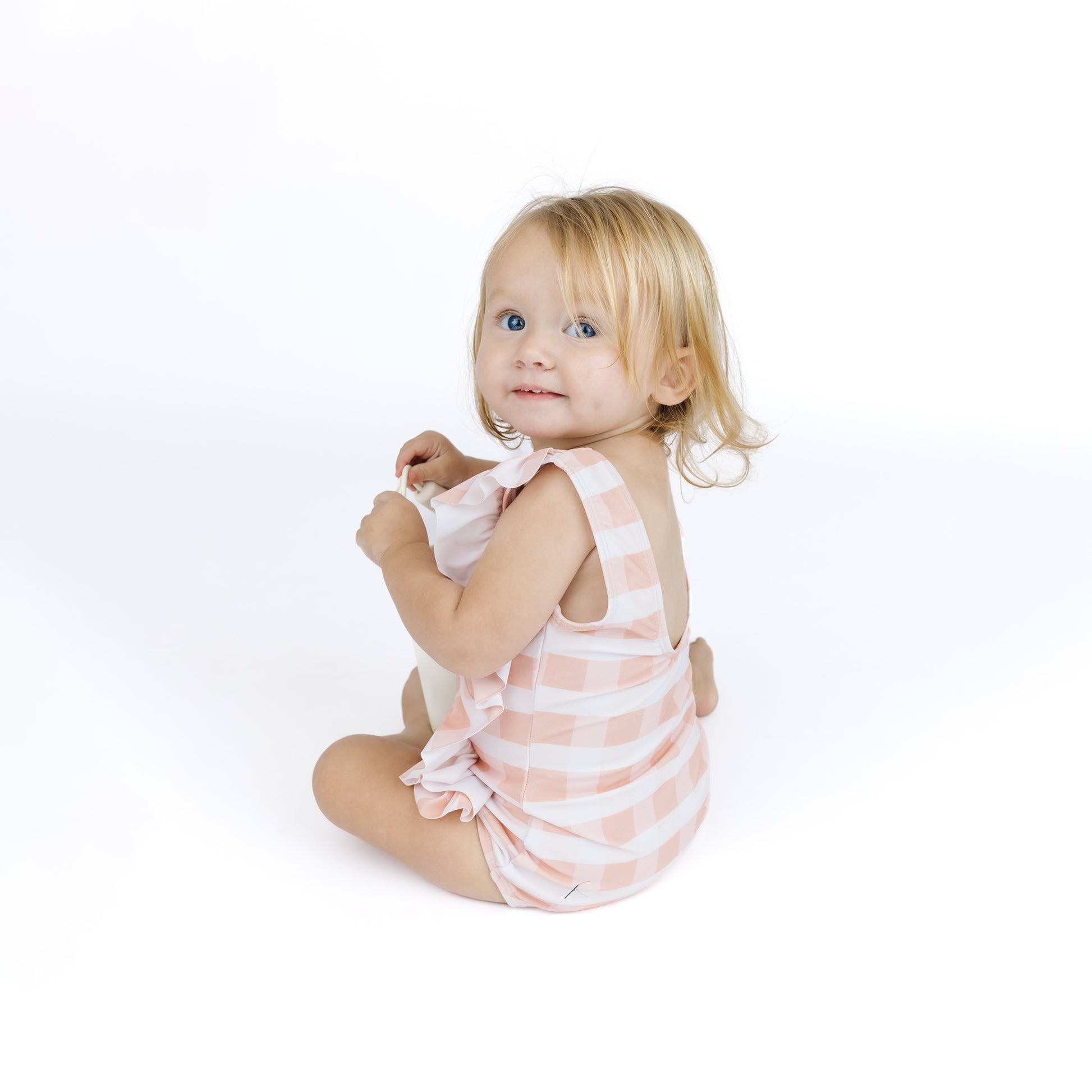 Young child wearing a pink and white striped dress on a white background