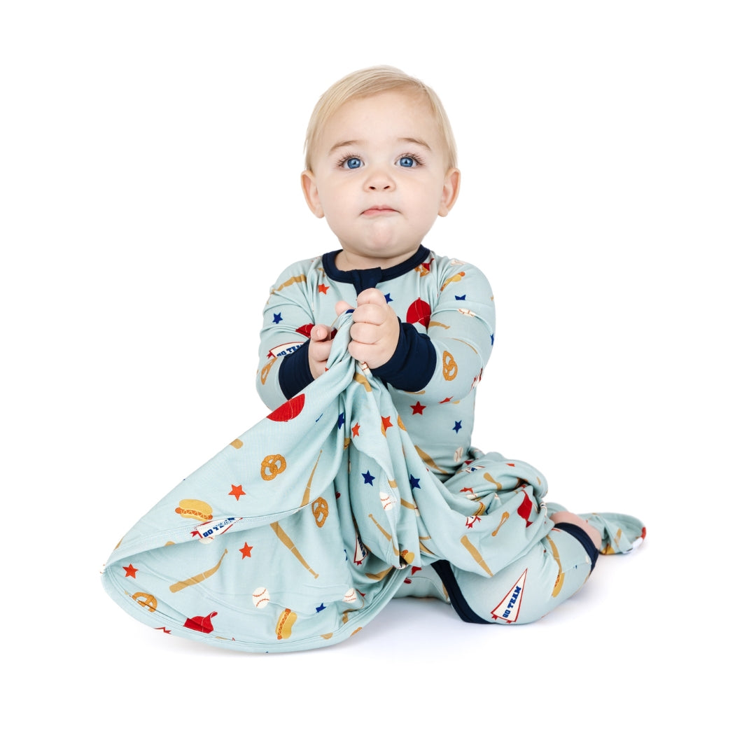 Baby in a colorful outfit holding a blanket on a white background
