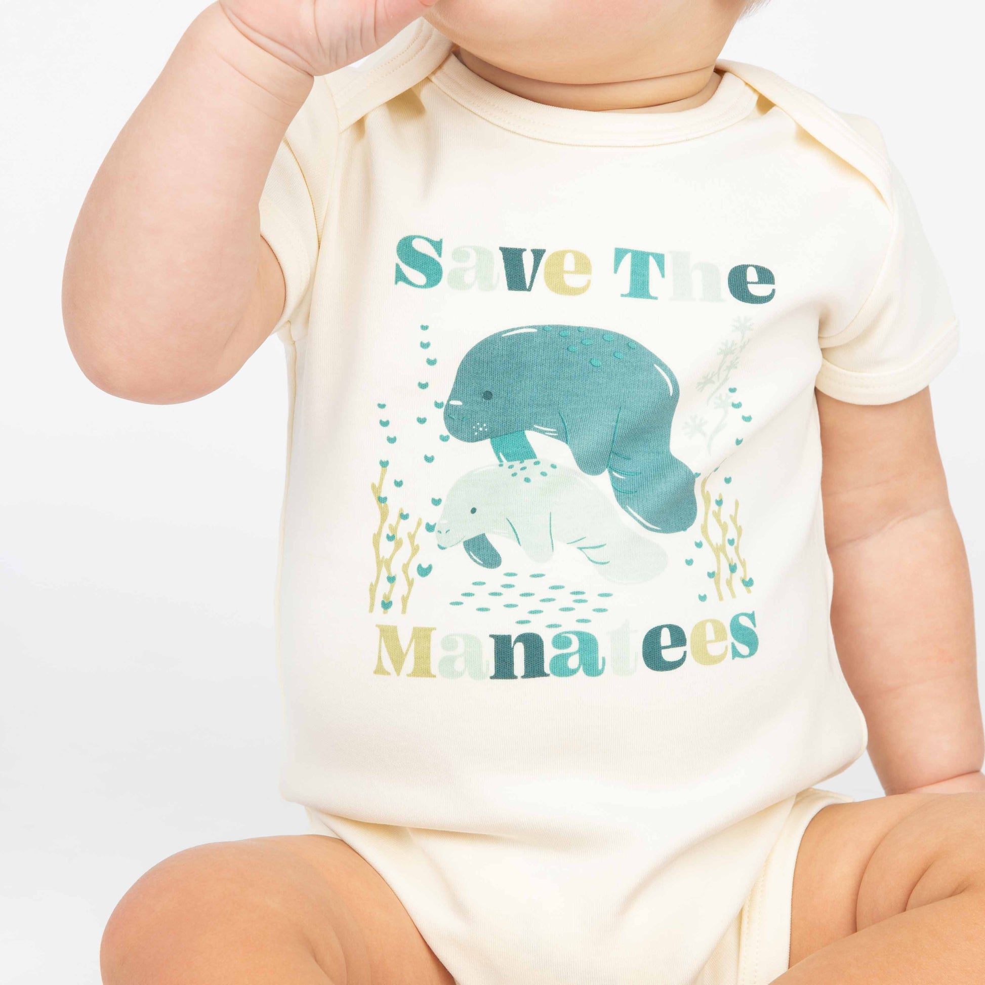 Baby wearing a Save the Manatees cotton bodysuit with a cute manatee print, featuring soft, eco-friendly fabric on a white background.