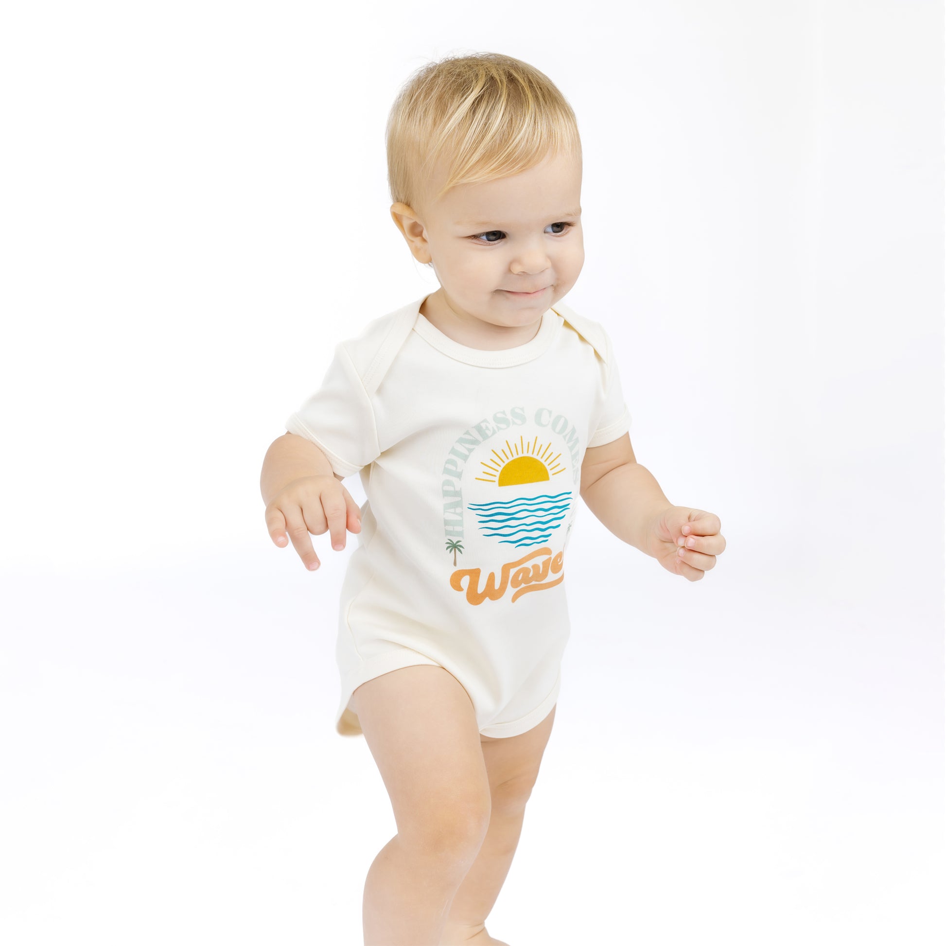 Baby wearing a white bodysuit with a beach graphic and text on a white background
