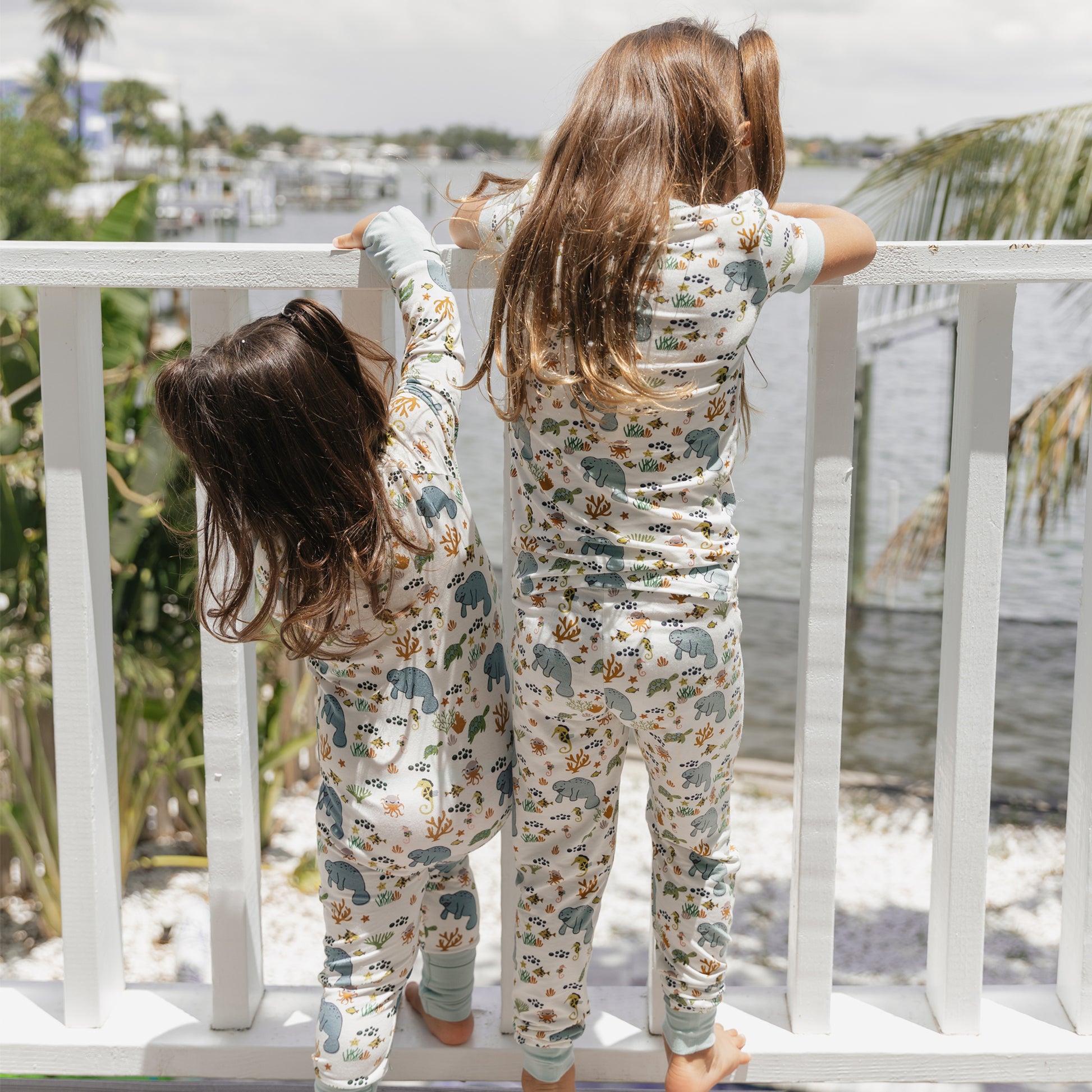 Back view of kids wearing manatee bamboo pajamas outdoors showing ocean print design