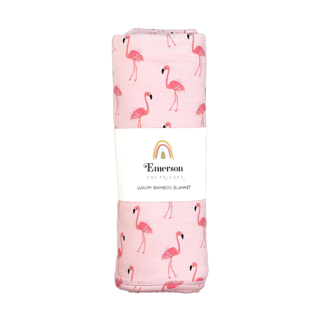 the "fancy flamingos" bamboo blanket in its packaging. the "fancy flamingos" print is a pattern of multiple pink flamingoes scattered around the print. 