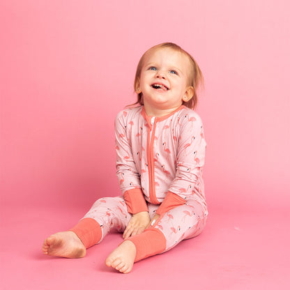 little girl in her "fancy flamingos" convertible. the "fancy flamingos" print is a pattern of multiple pink flamingoes scattered around the print. 