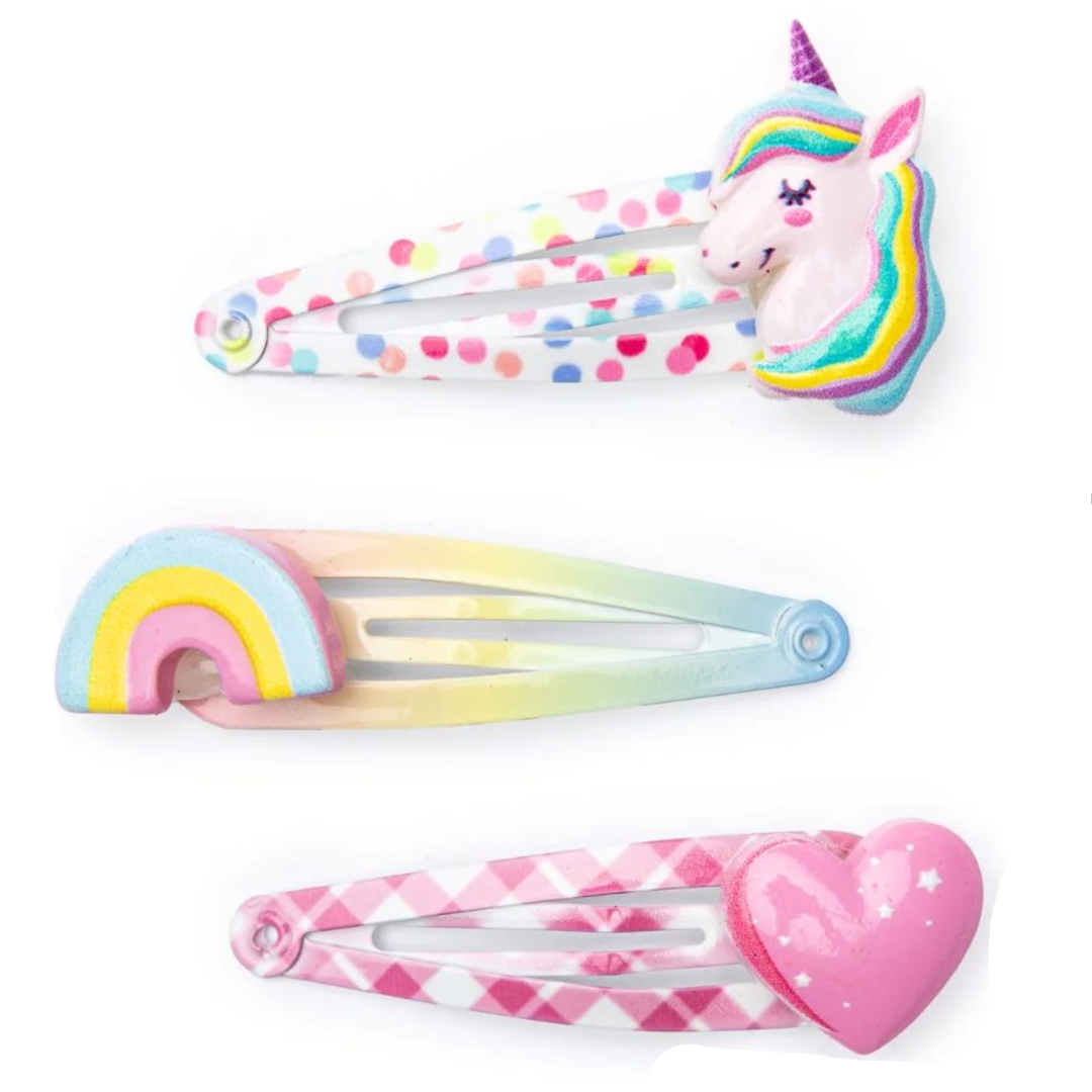 3 hair clips, one is polka dotted with a unicorn head on the top, one is rainbow ombre with a rainbow charm on the top, and one is white and pink gingham with a pink heart on top