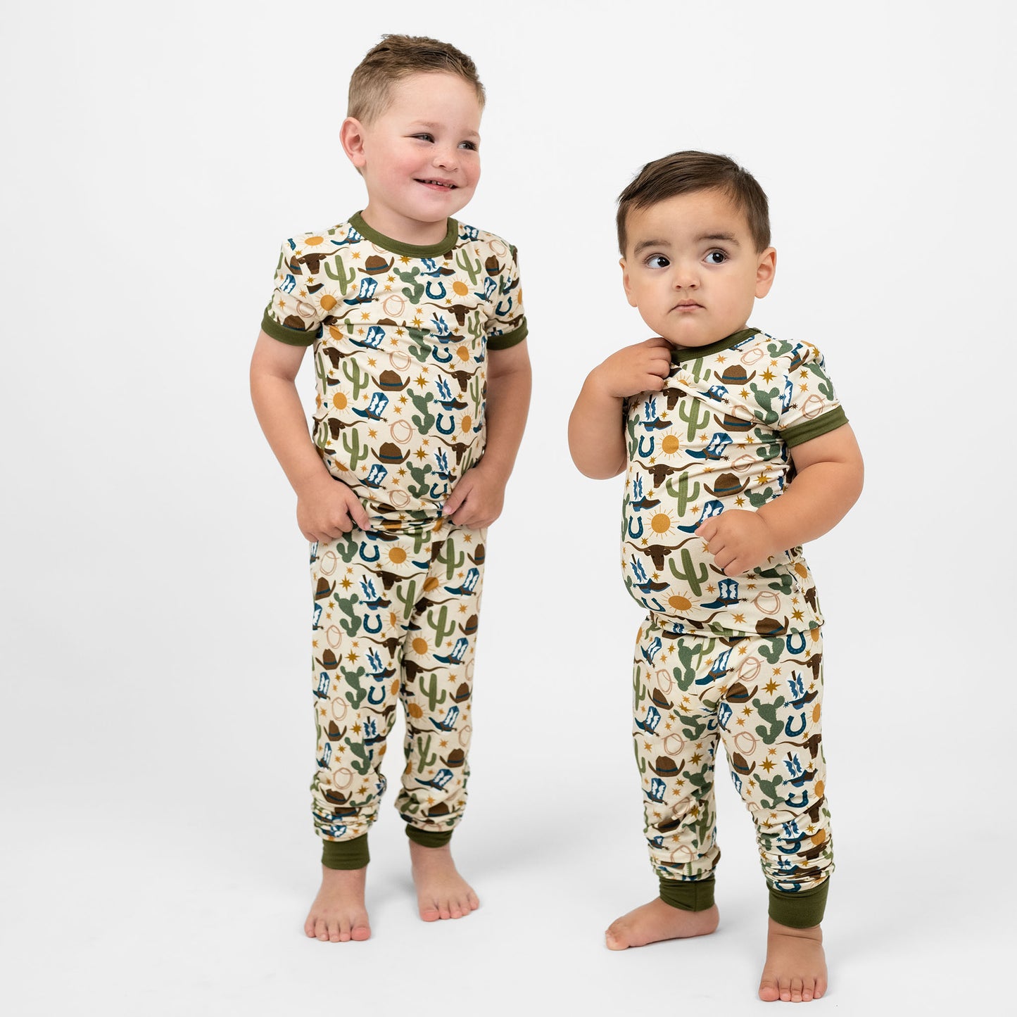 Brothers wearing our Western Howdy Collection! This cozy bamboo 2-piece pajama features a charming cowboy-themed print with blue boots, cacti, suns, horseshoes, and cowboy hats. Perfect for western cozy vibes. 